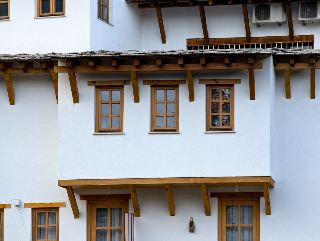 Close-up of traditional white house featuring wooden windows and roof elements.