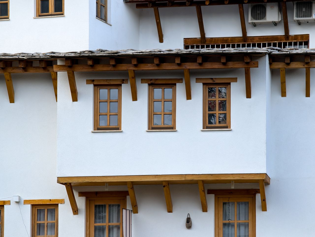 Close-up of traditional white house featuring wooden windows and roof elements.